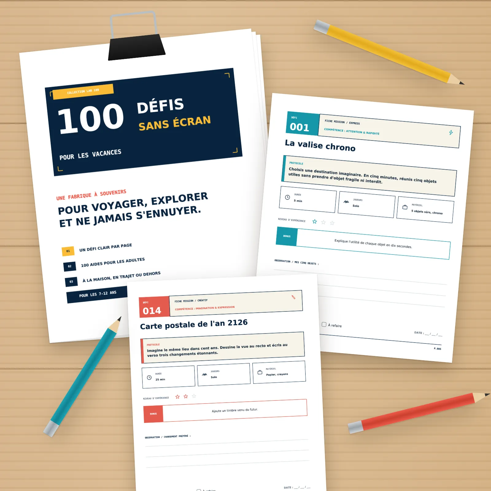 Pages imprimées du PDF sur une table en bois : page de titre sur une pile tenue par une pince, défis 001 et 014, crayons de couleur