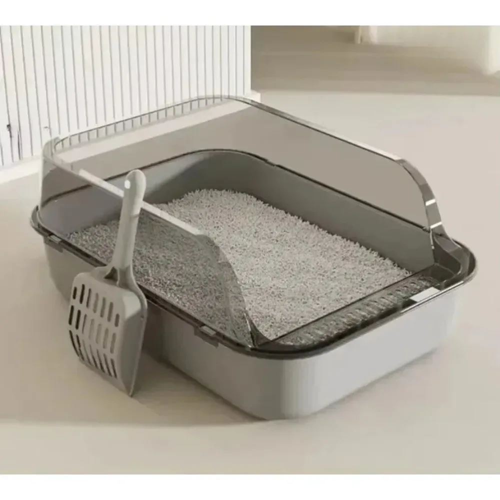 Bac à litière gris semi-fermé avec sa pelle, rempli de litière, vu de trois quarts