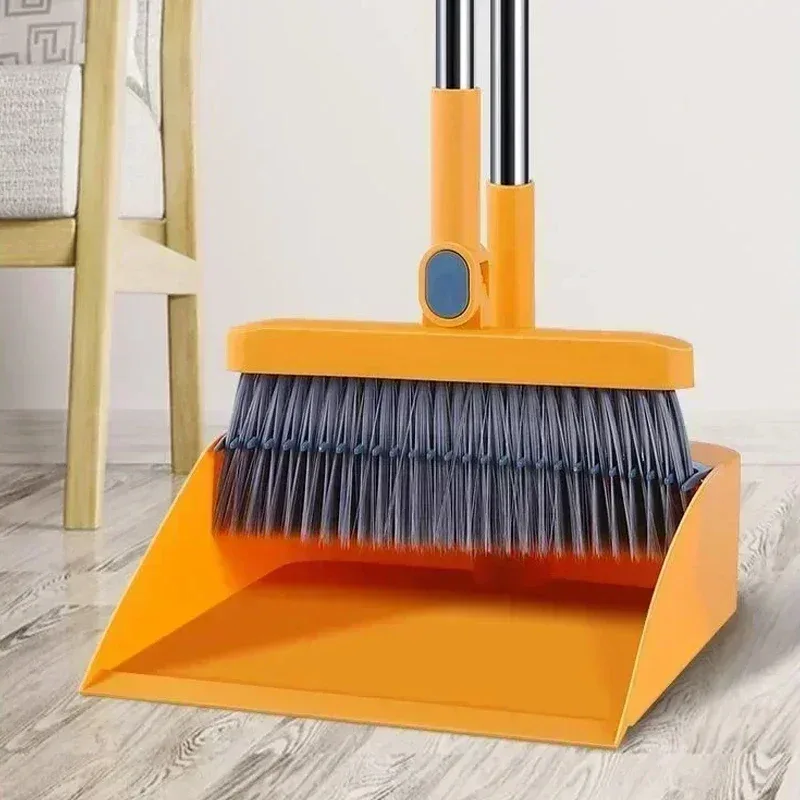 Pelle à poussière orange à bord denté et balai à poils gris, posés sur un parquet