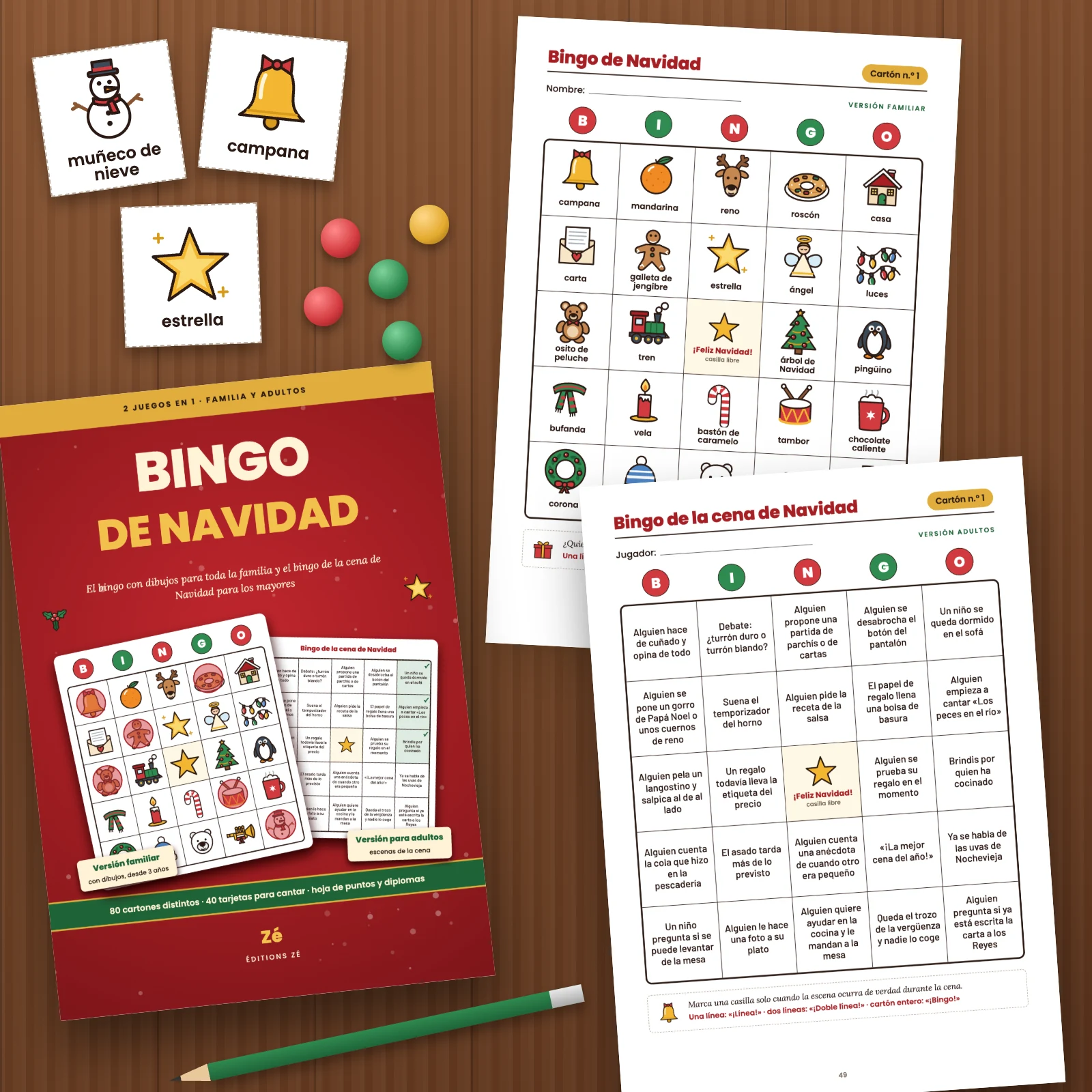 La portada y dos páginas impresas del PDF sobre una mesa de madera: el cartón familiar n.º 1 con dibujos y el cartón n.º 1 del bingo de la cena de Navidad, con tres tarjetas recortadas (muñeco de nieve, campana, estrella), fichas y un lápiz