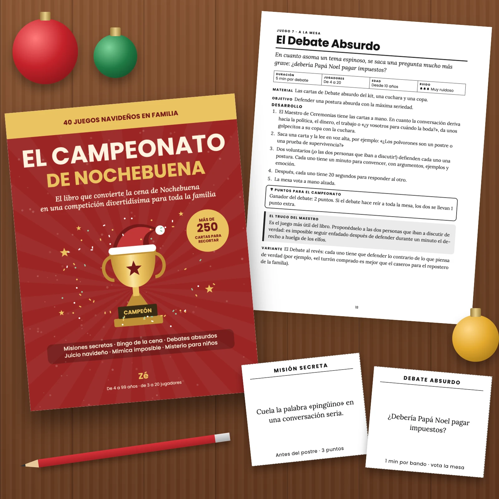 La portada y páginas impresas del PDF sobre una mesa de madera: la ficha del juego 7 «El Debate Absurdo», una carta Misión secreta «Cuela la palabra “pingüino” en una conversación seria» y una carta Debate absurdo «¿Debería Papá Noel pagar impuestos?», con bolas de Navidad y un lápiz