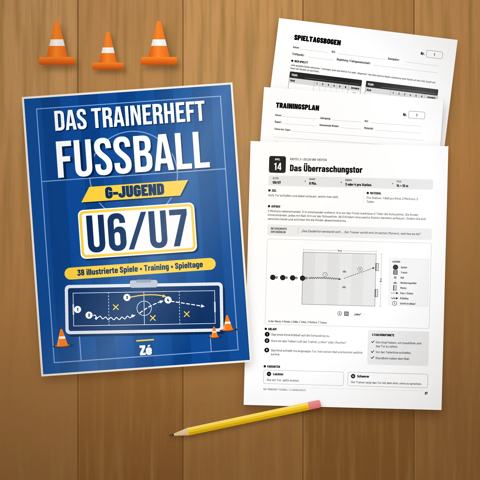 Das Buch auf einem Holztisch neben drei ausgedruckten Seiten des PDFs: Spiel 14 „Das Überraschungstor“, ein Trainingsplan und ein Spieltagsbogen, mit Bleistift und orangen Hütchen