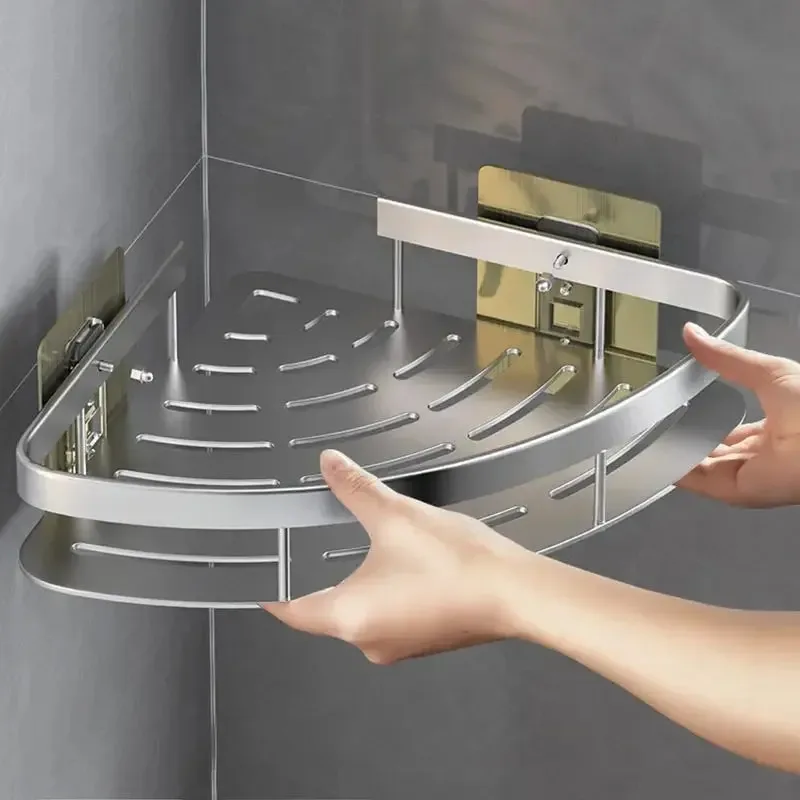 Mains qui présentent l'étagère d'angle en aluminium argenté, avec son rebord et sa plaque adhésive