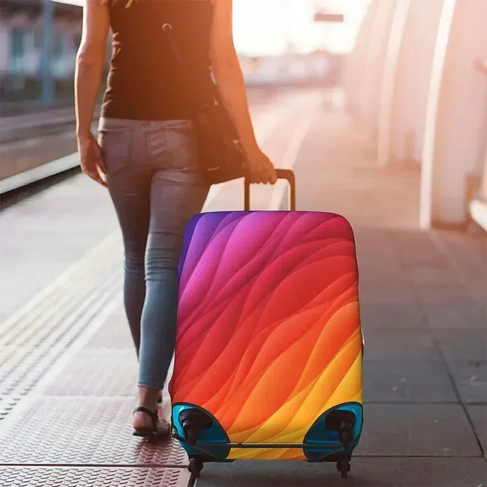 Femme tirant une valise recouverte d'une housse élastique colorée dans une gare