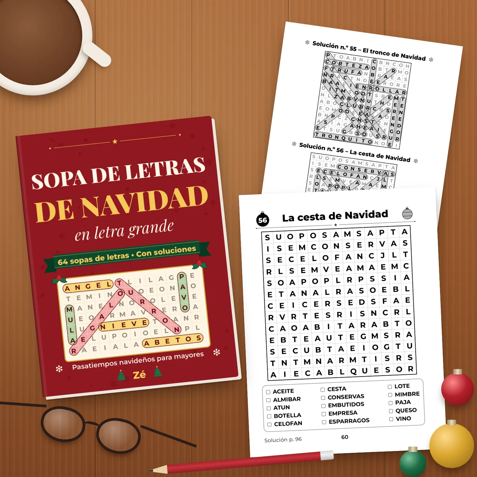 El libro sobre una mesa de madera con dos páginas impresas (la sopa n.º 56 «La cesta de Navidad» y una página de soluciones), una taza, unas gafas, un lápiz y bolas de Navidad