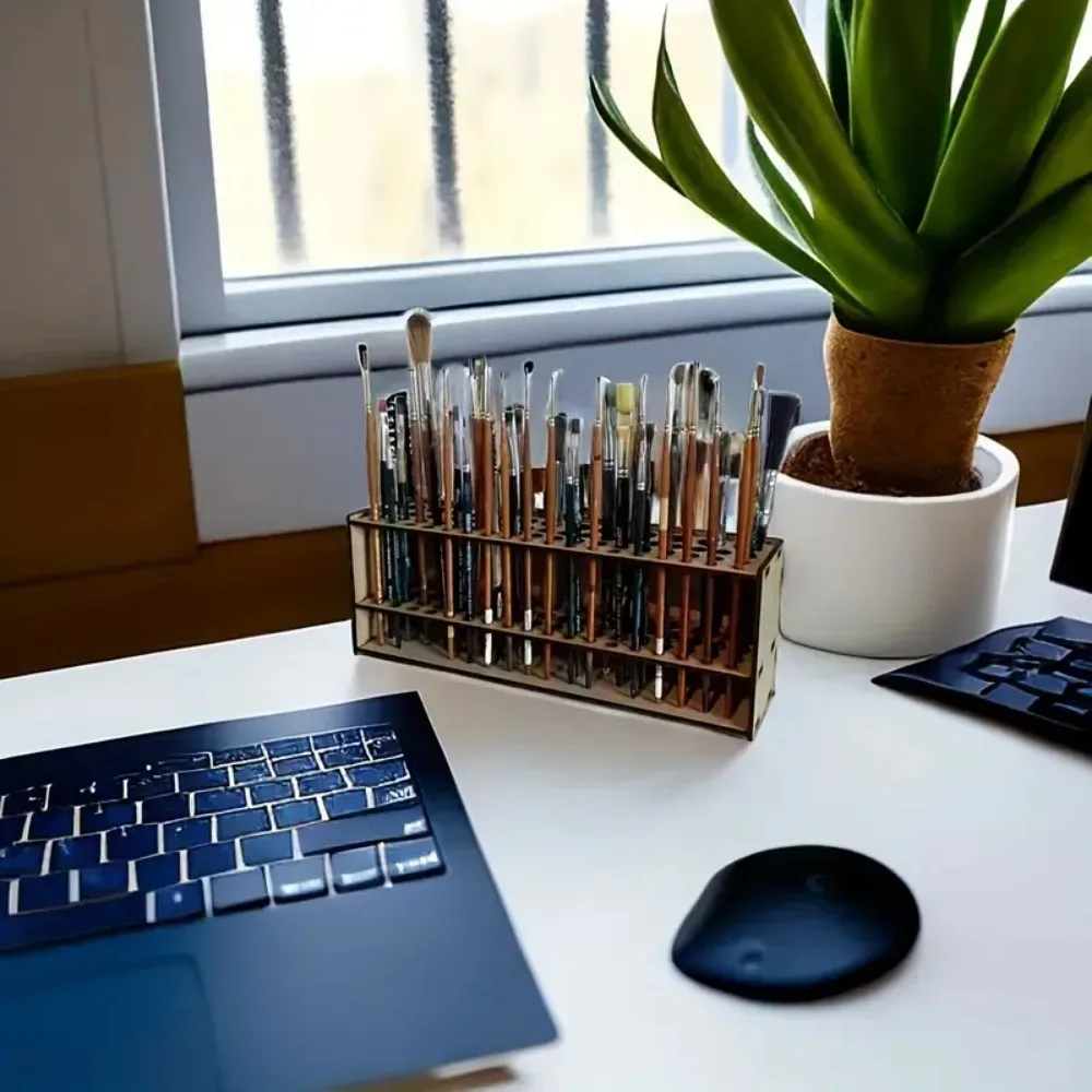 Porte-pinceaux en bois sur un bureau, à côté d'un ordinateur portable, avec une plante