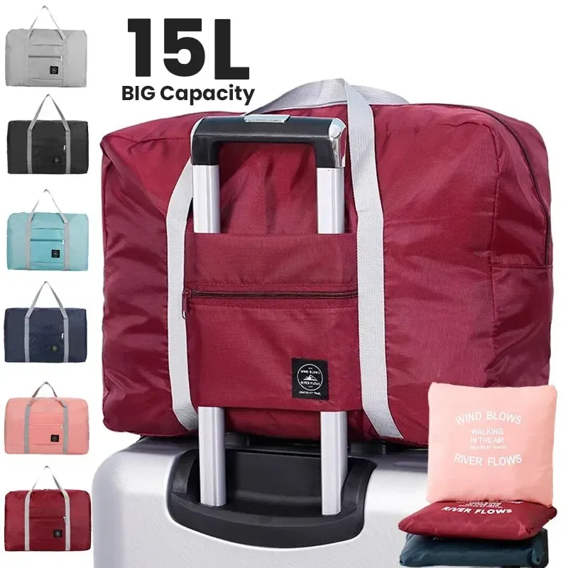 Sac de voyage pliable rouge bordeaux à anses grises, glissé sur la poignée d'une valise, avec sa pochette de rangement rose
