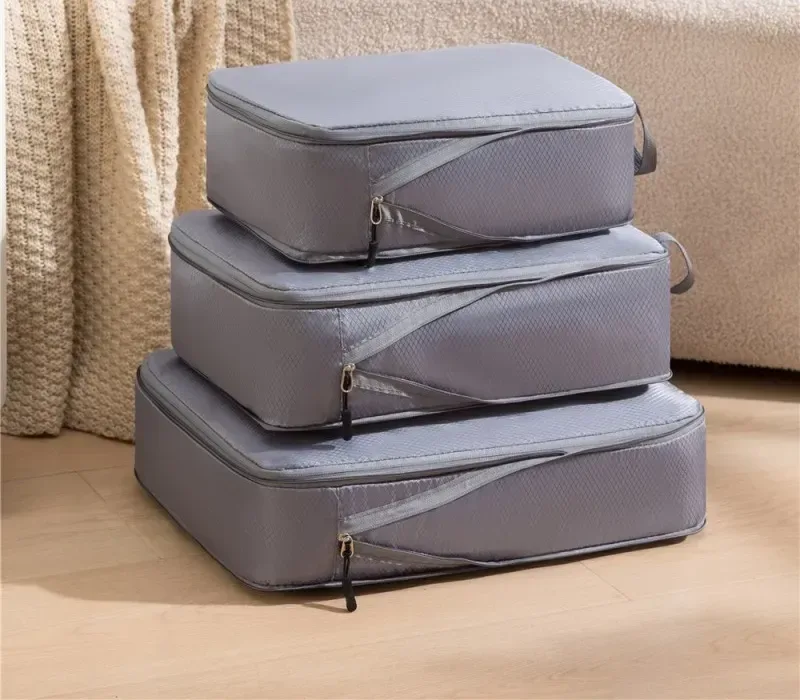 Trois sacs de rangement compressibles gris de tailles différentes, empilés les uns sur les autres