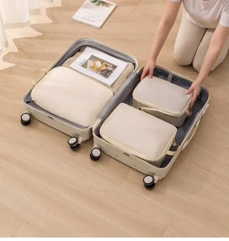 Femme qui range des sacs de rangement beiges dans une valise ouverte (exemple en beige)